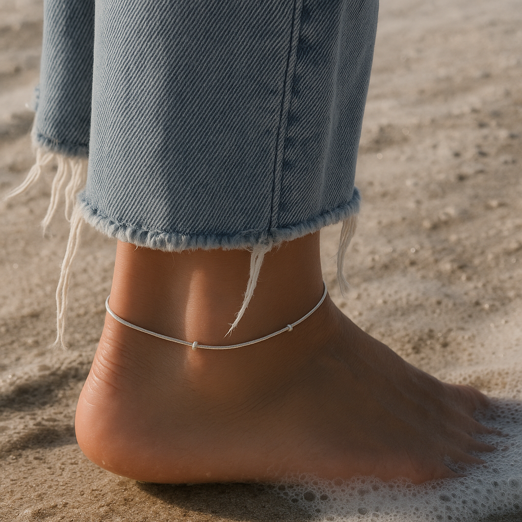 Close-up of a foot wearing a anklet on a sandy background