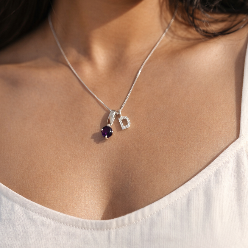 Woman wearing a necklace with a pendant, close-up of her neck and shoulders.