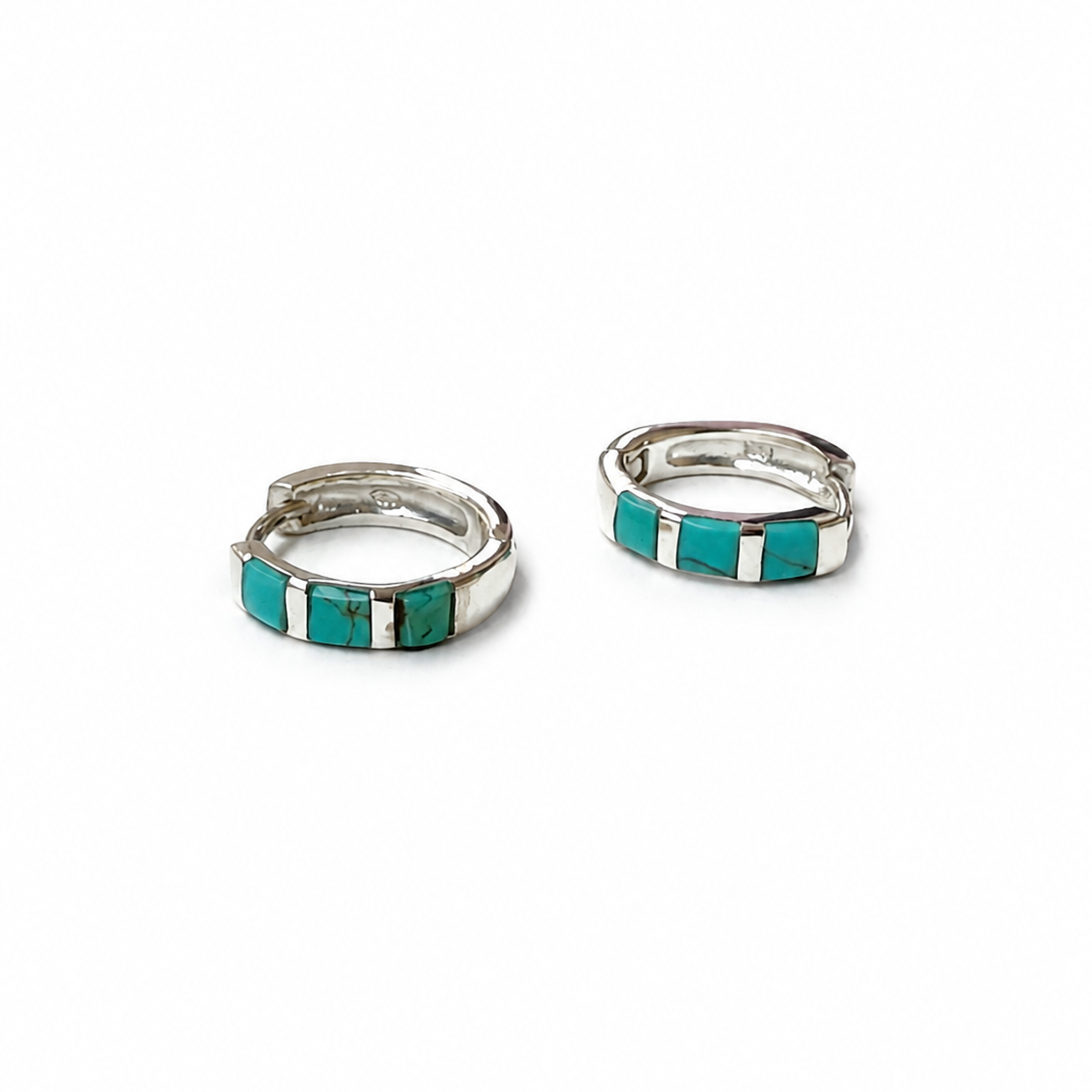 A pair of silver huggie hoop earrings with inlaid turquoise and white stone accents, displayed on a clean white background.