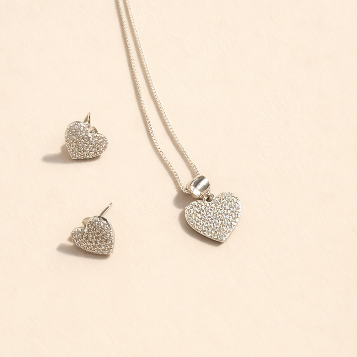 Heart-shaped jewelry set with necklace and earrings on a beige background