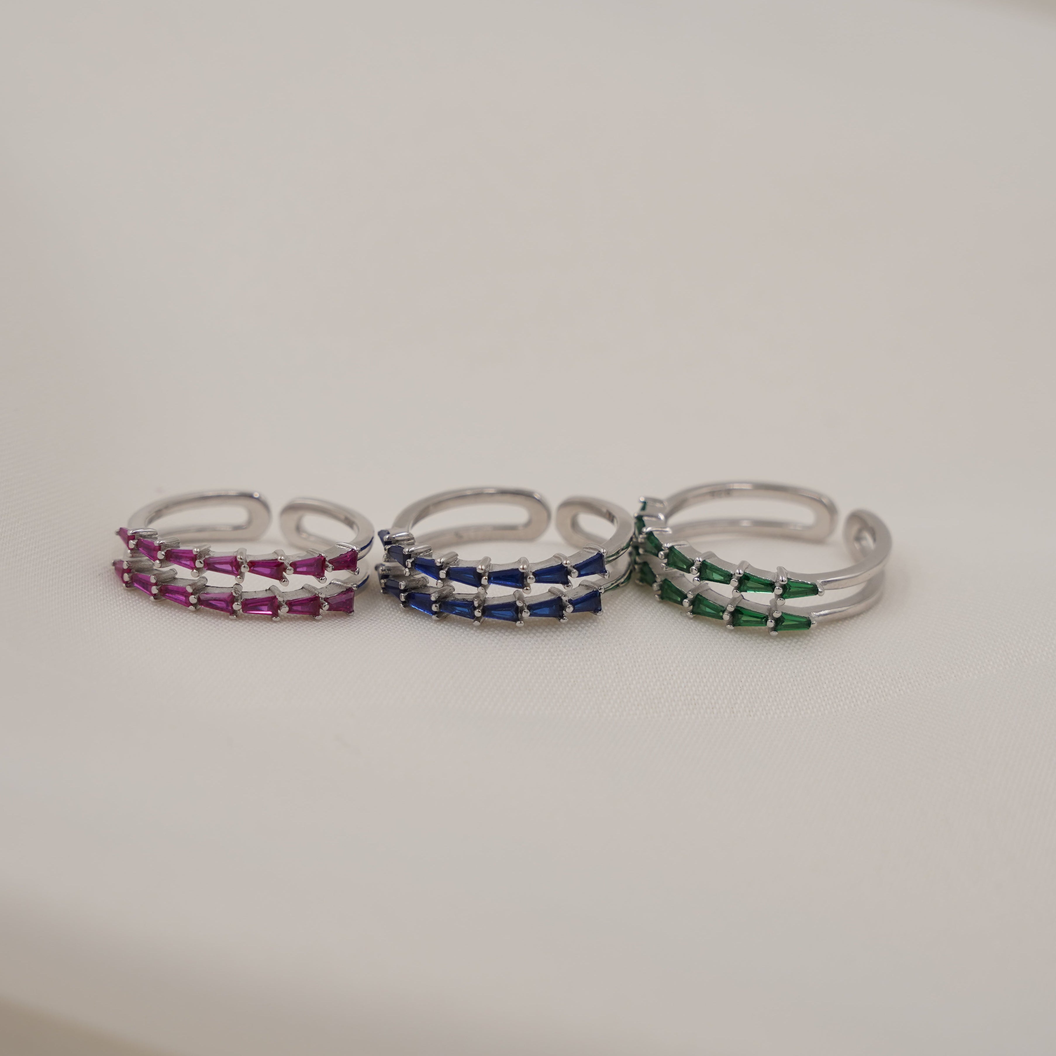 Three silver rings with colorful stones on a white surface