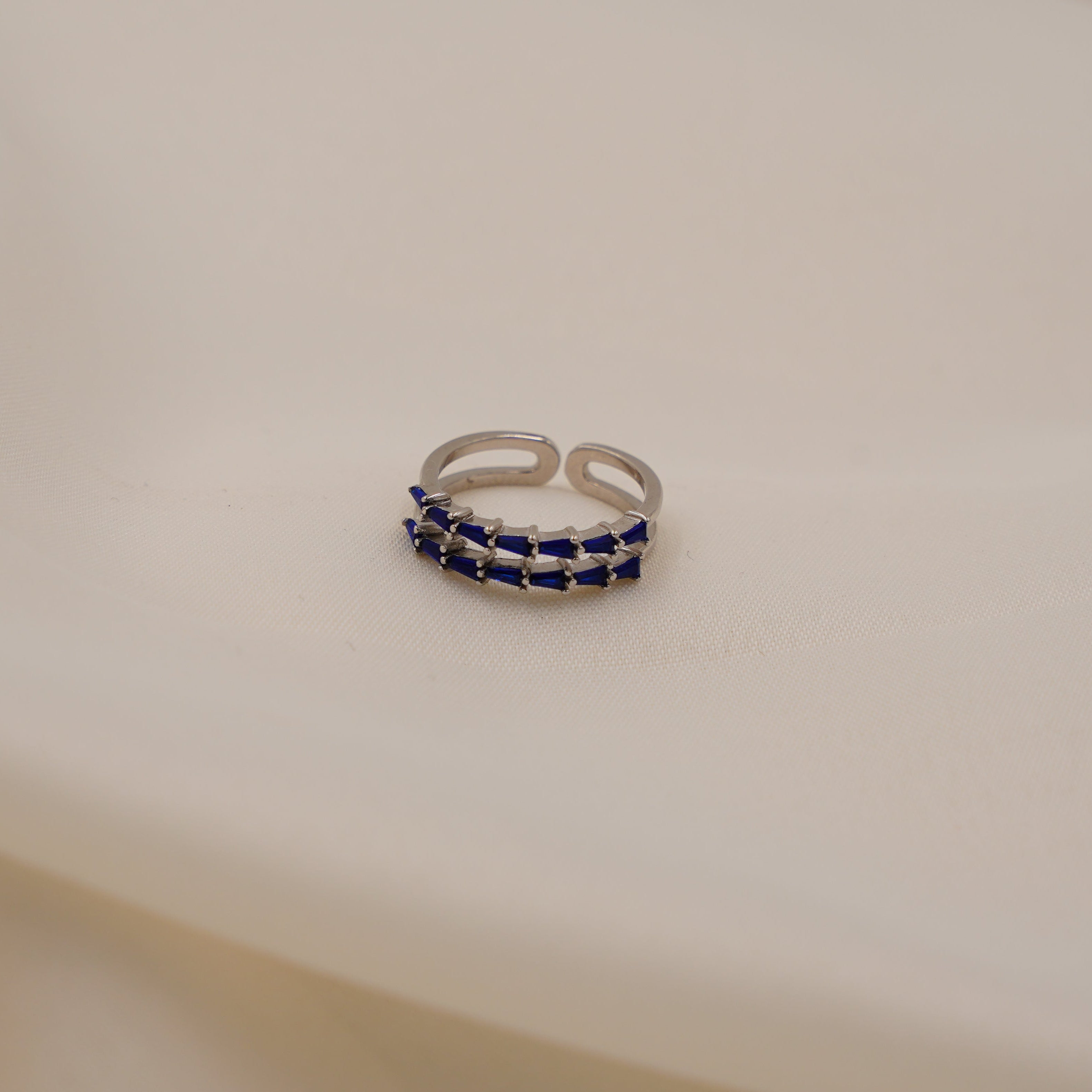 Silver ring with blue stones on a beige fabric background