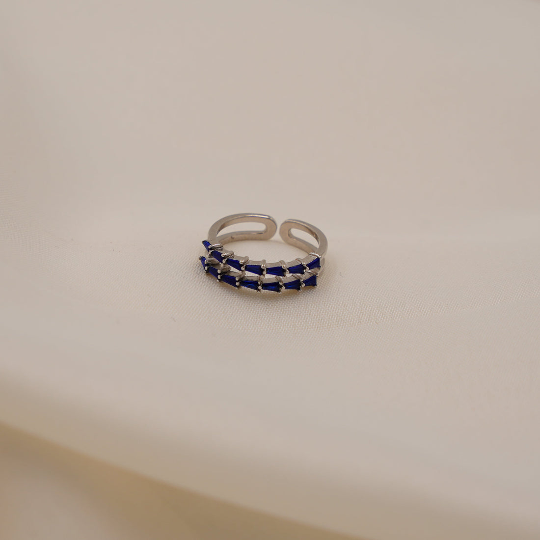 Silver ring with blue stones on a beige fabric background