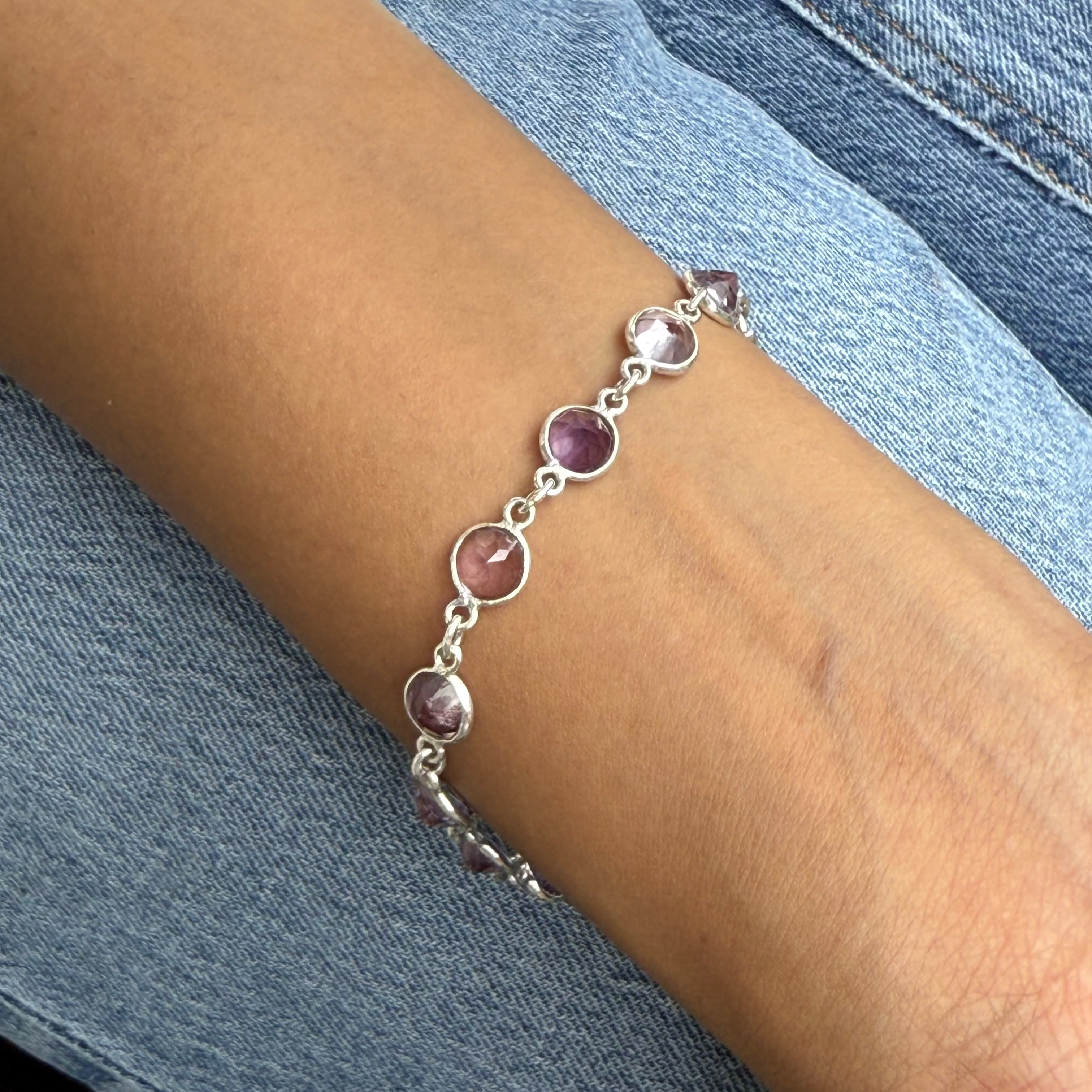 Bracelet with purple gemstones on a wrist against a denim background