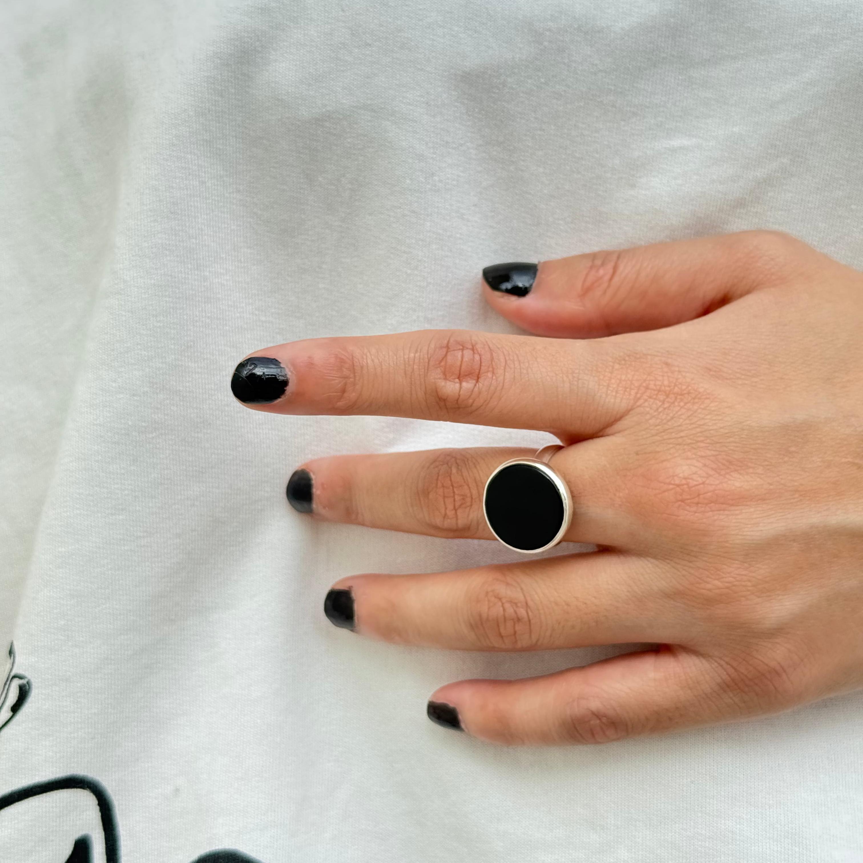 Hand wearing a black ring on a white background