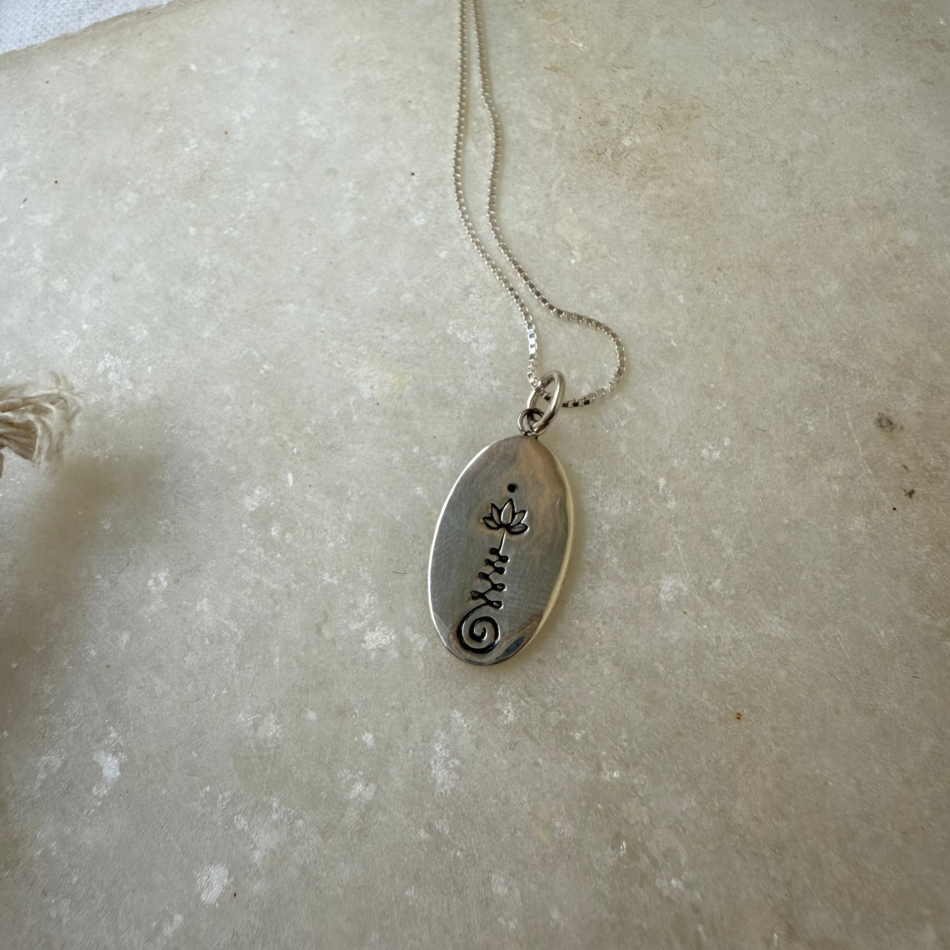 Silver necklace with a pendant on a marble surface
