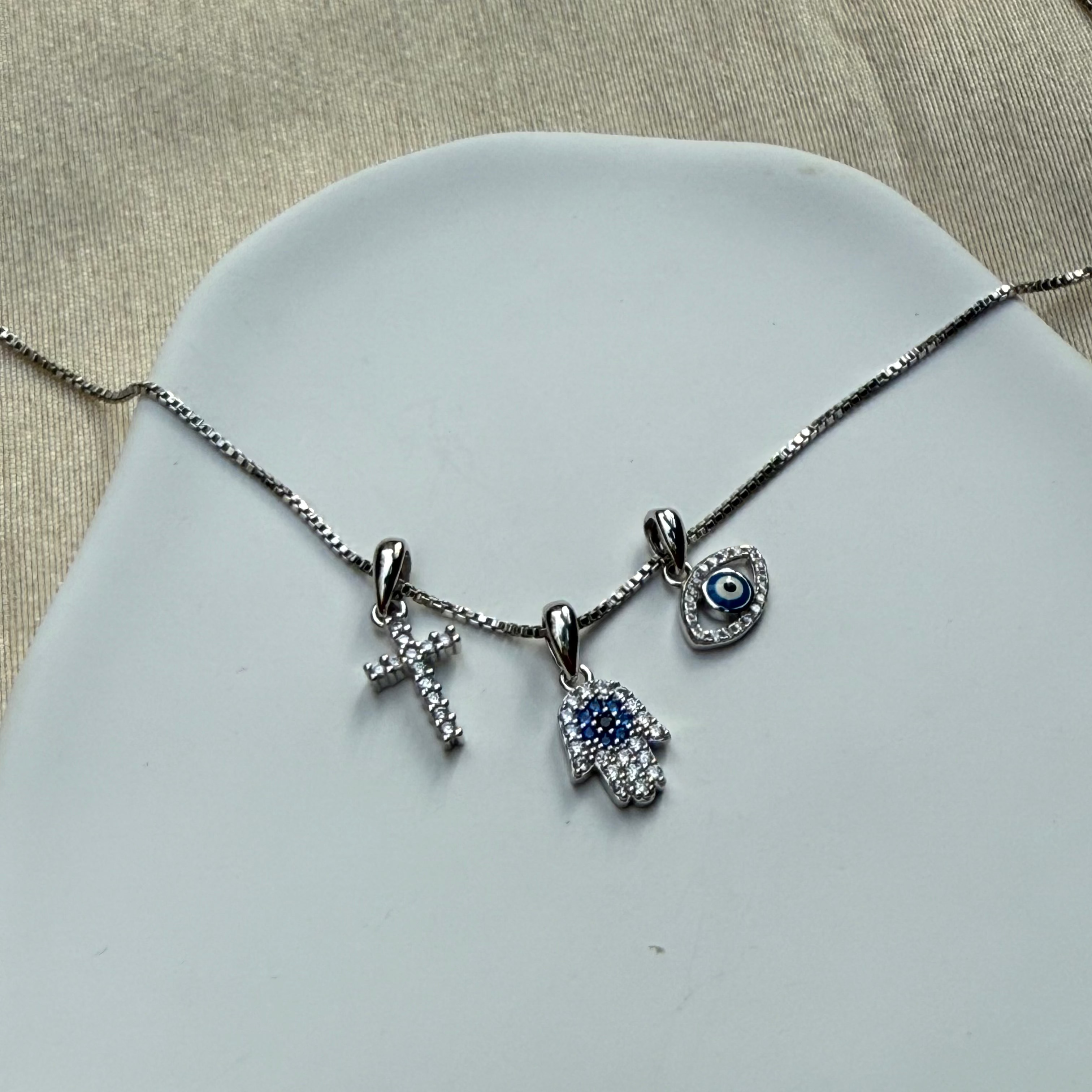 Necklace with three charms on a light gray surface