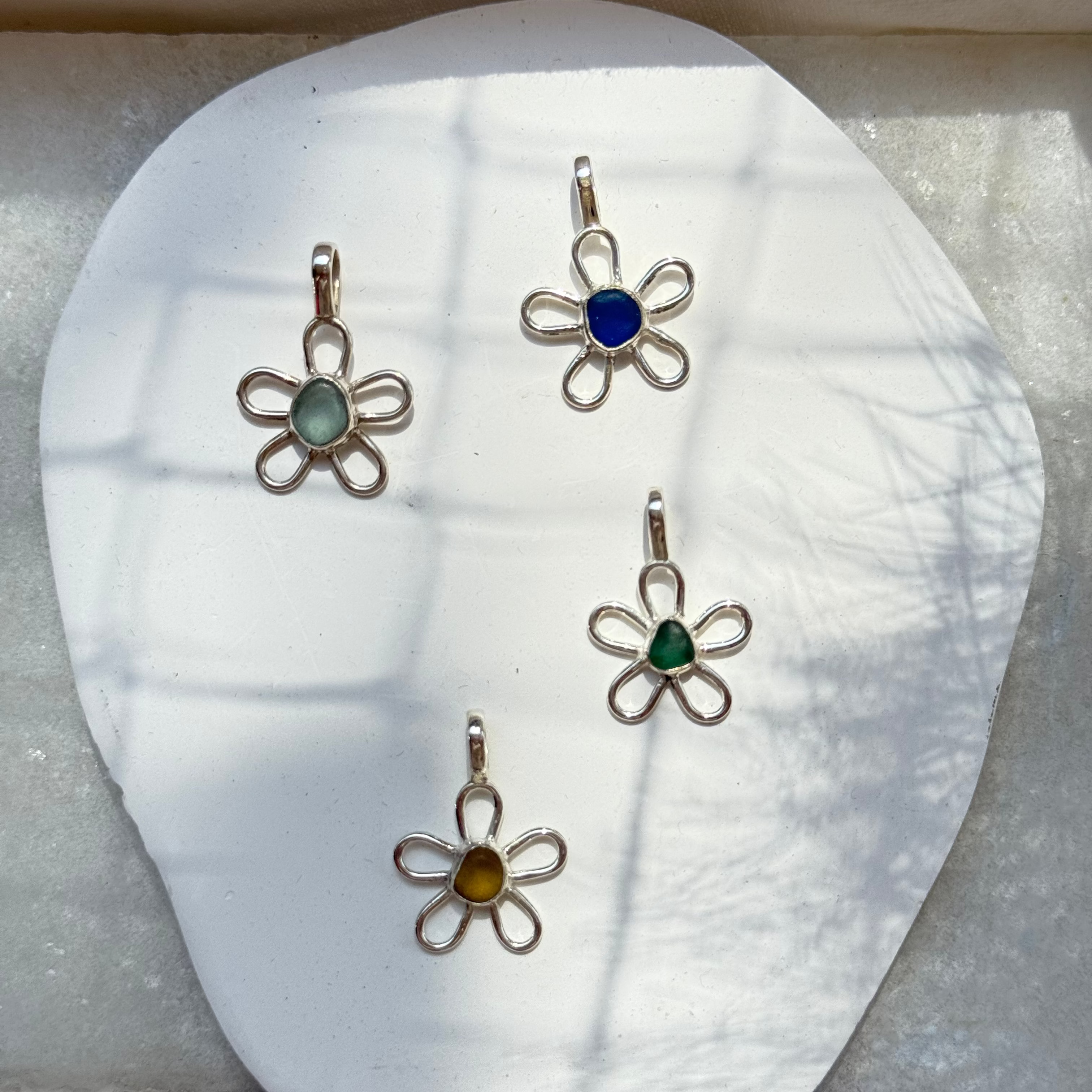Three flower-shaped pendants on a white shell