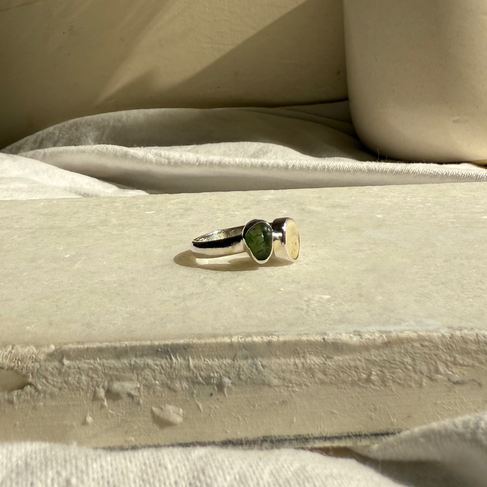 Ring on a stone surface with a vase and dried plants in the background