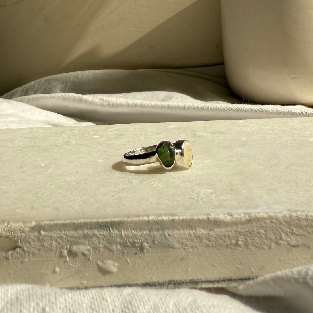 Ring on a stone surface with a vase and dried plants in the background