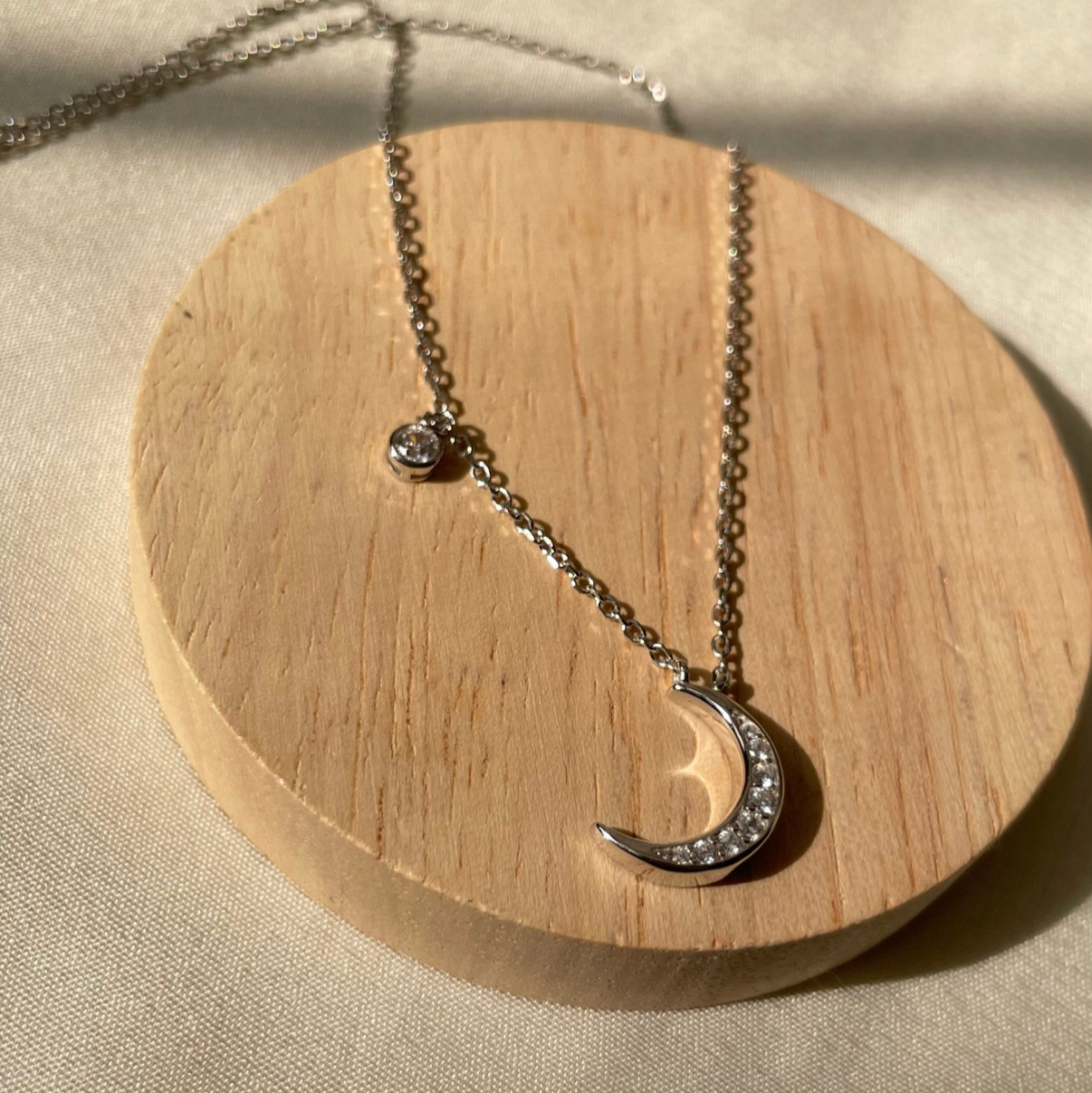 Necklace with a moon-shaped pendant on a wooden stand