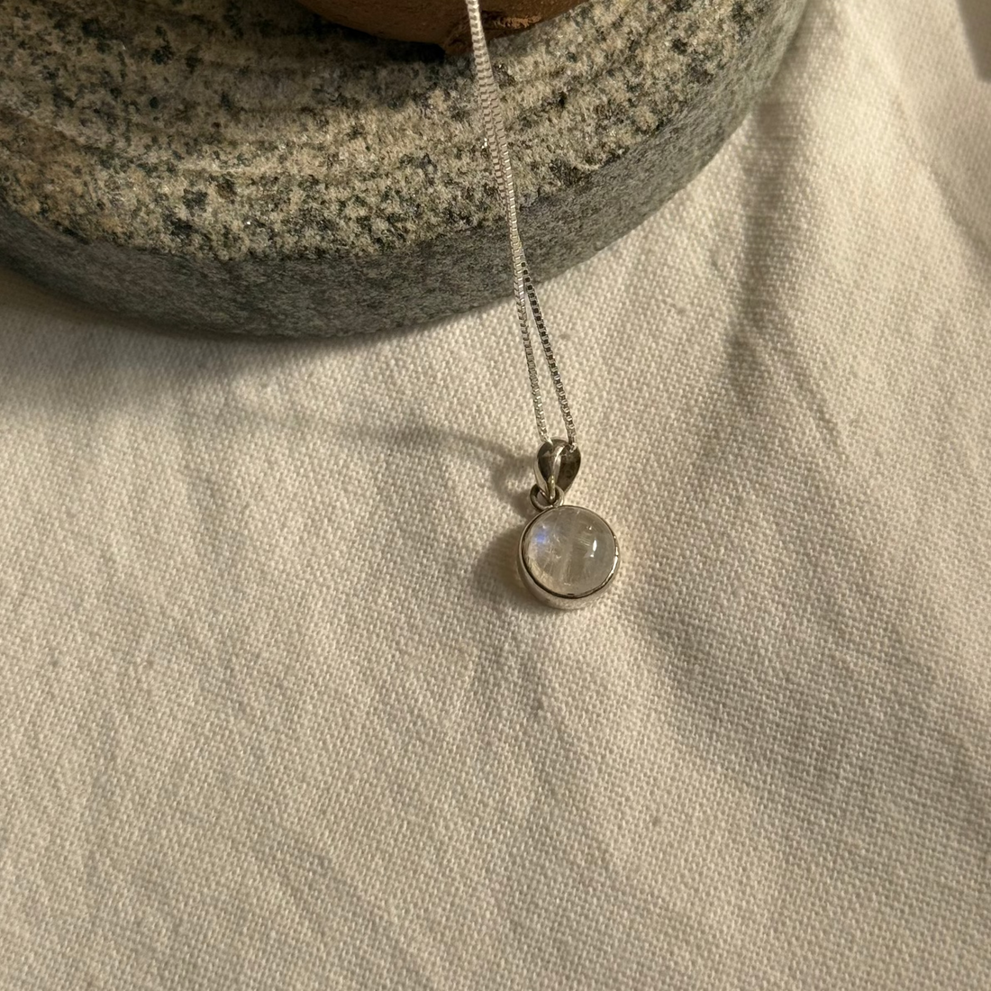 Silver necklace with a pendant on a textured surface