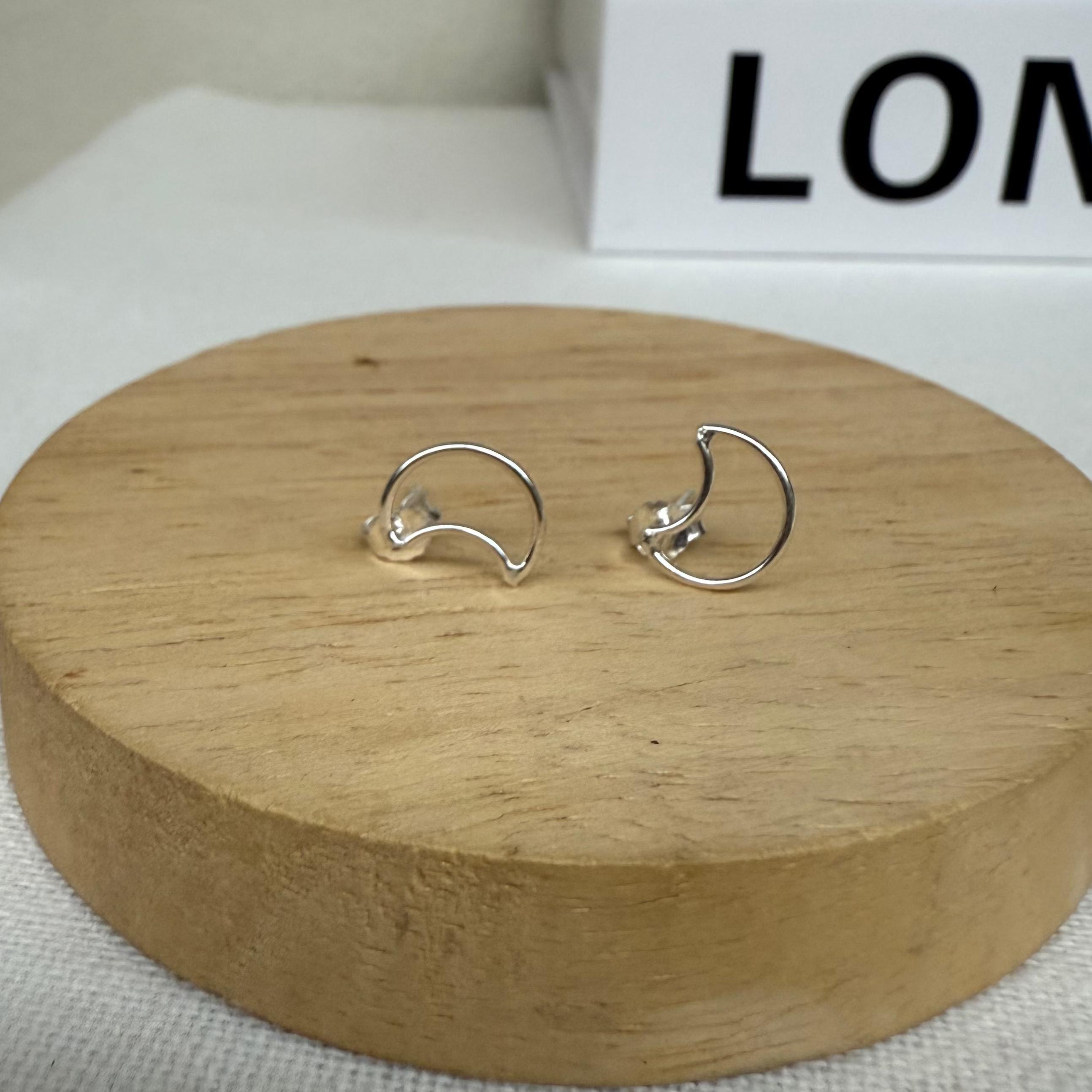 Silver earrings on a wooden stand with a white background