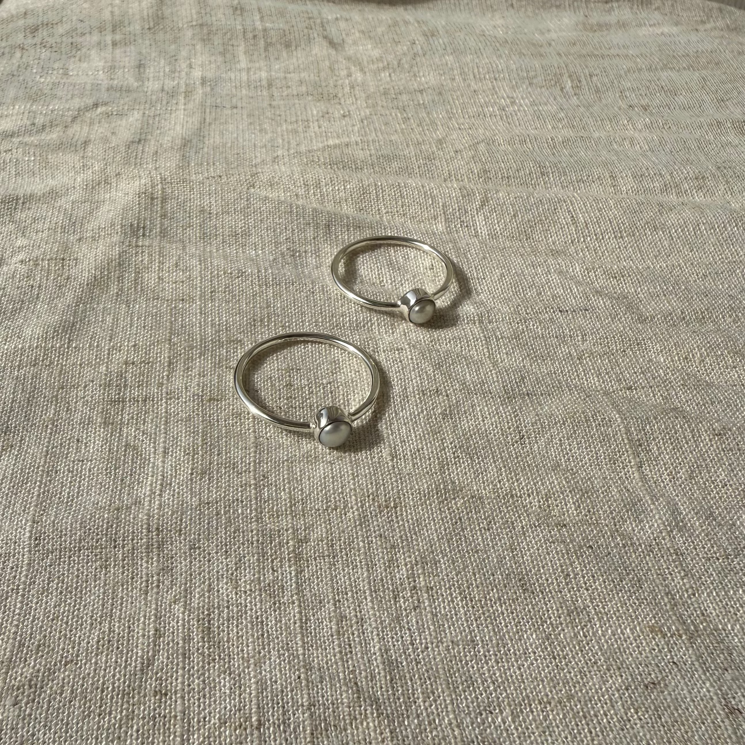 Two silver rings on a textured beige surface