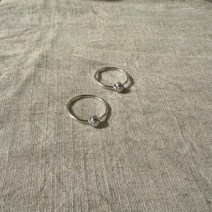 Two silver rings on a textured beige surface