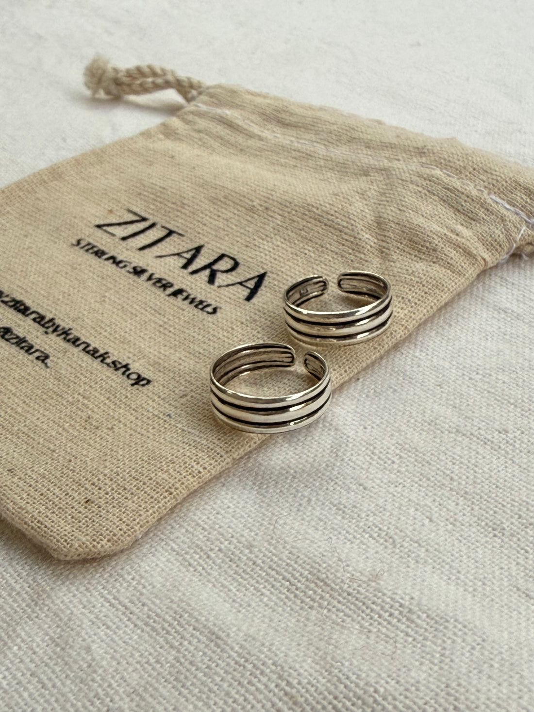 Two silver rings on a beige drawstring bag with 'Zitara' branding.