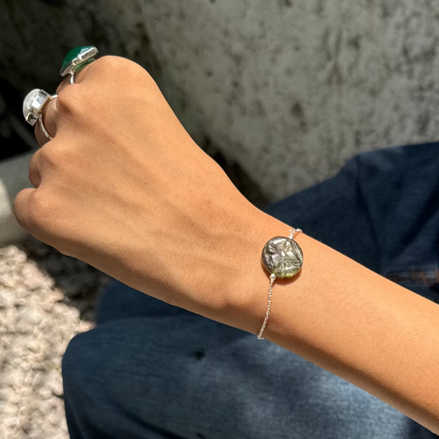 Person wearing a ring and sitting on a concrete surface