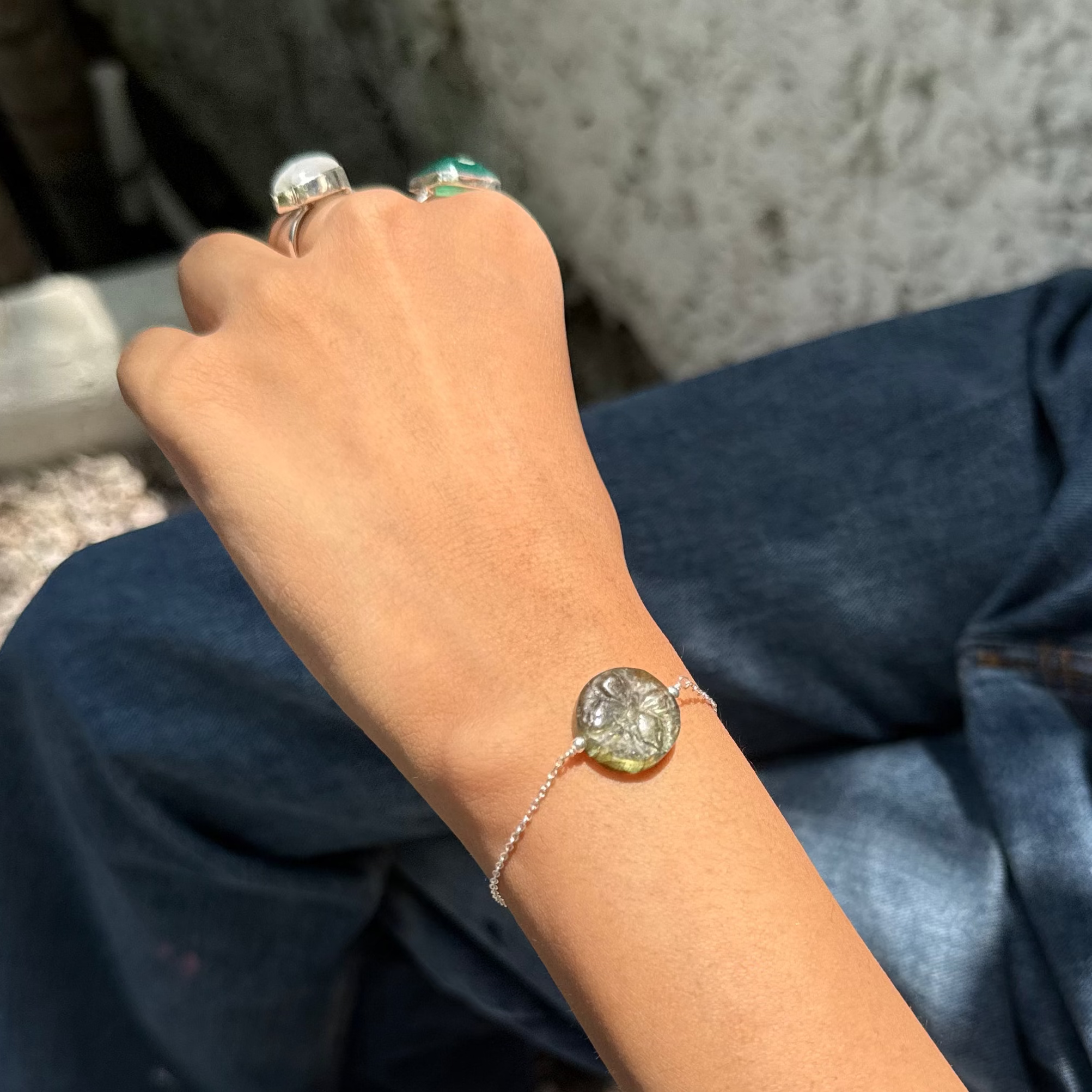 Person wearing a bracelet and ring with a textured wall background