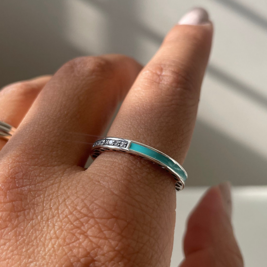 Close-up of a hand wearing two silver rings with a light background