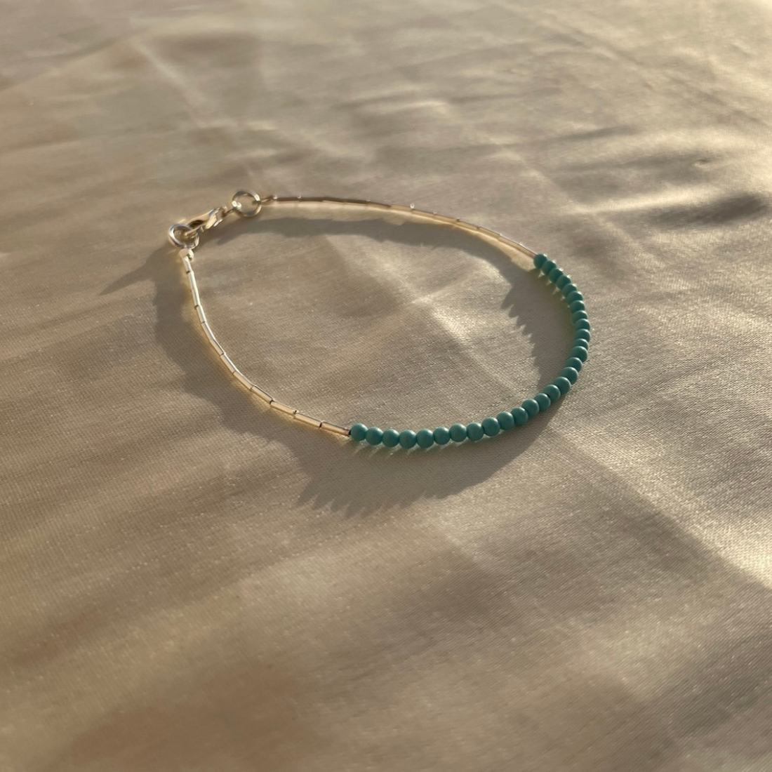 Bracelet with green beads on a beige surface