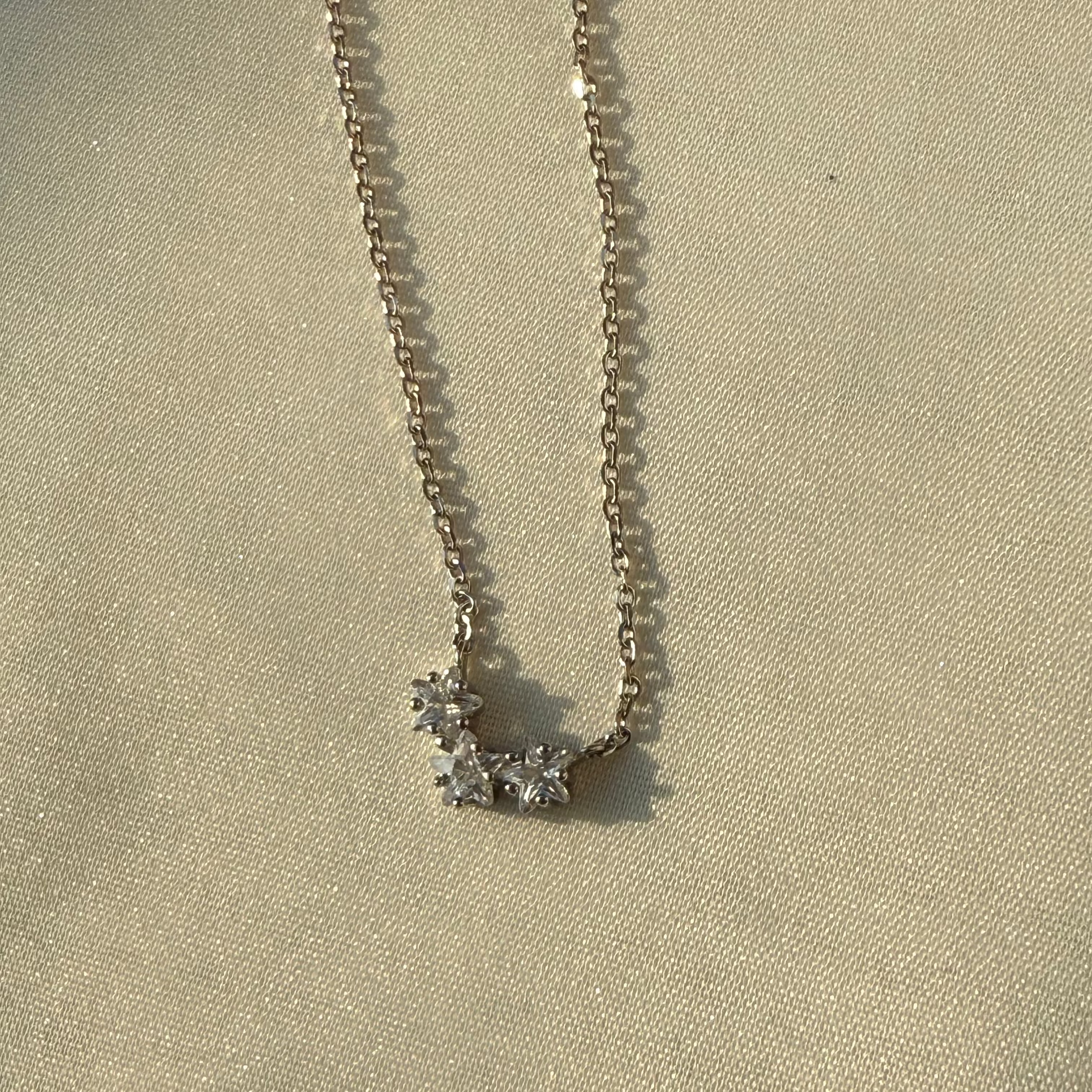 Silver necklace with a star-shaped pendant on a beige fabric background