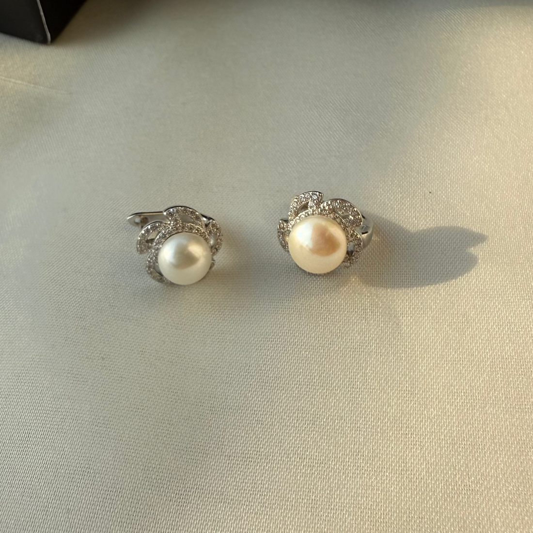 Pair of pearl earrings on a light fabric surface