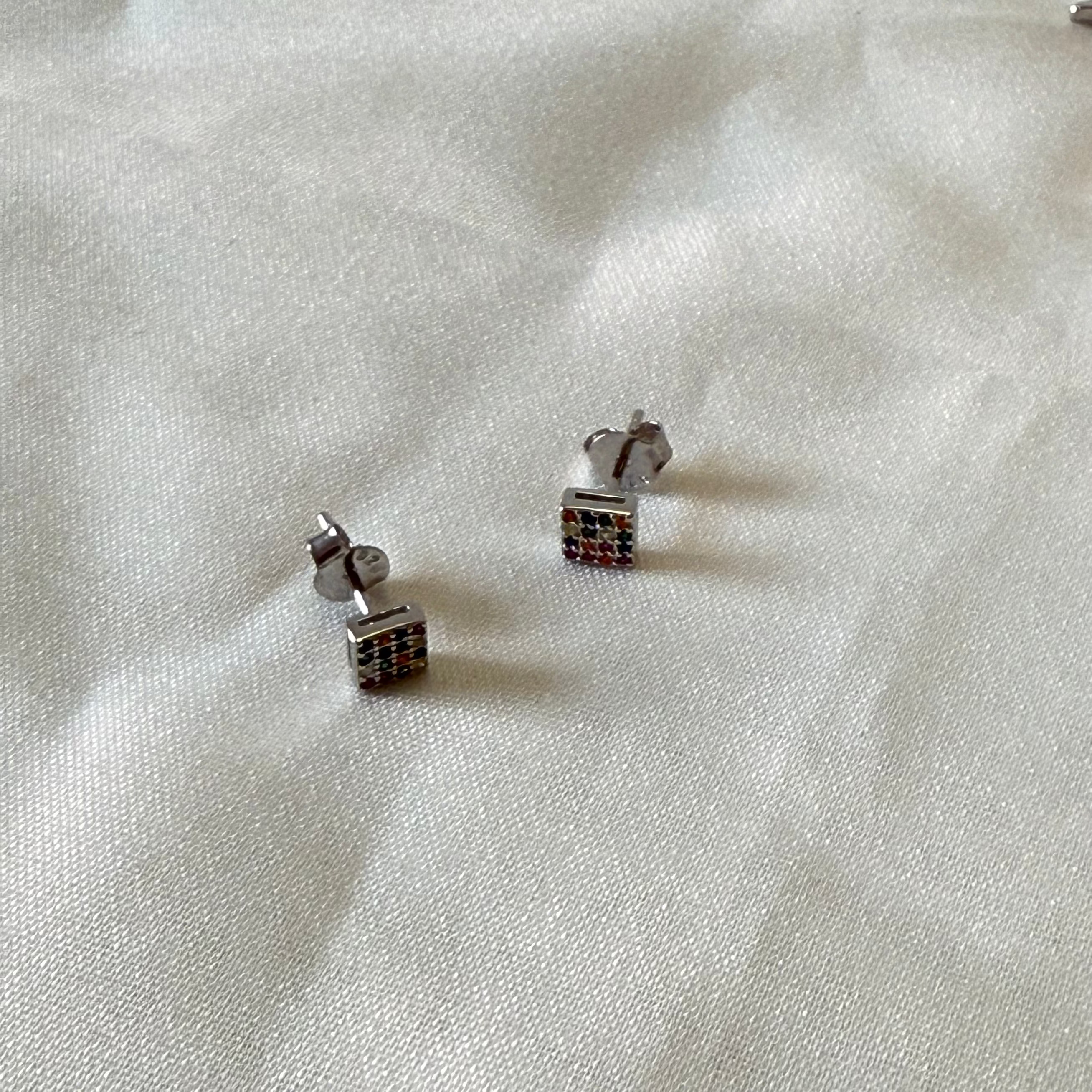 Pair of silver earrings on a white fabric background