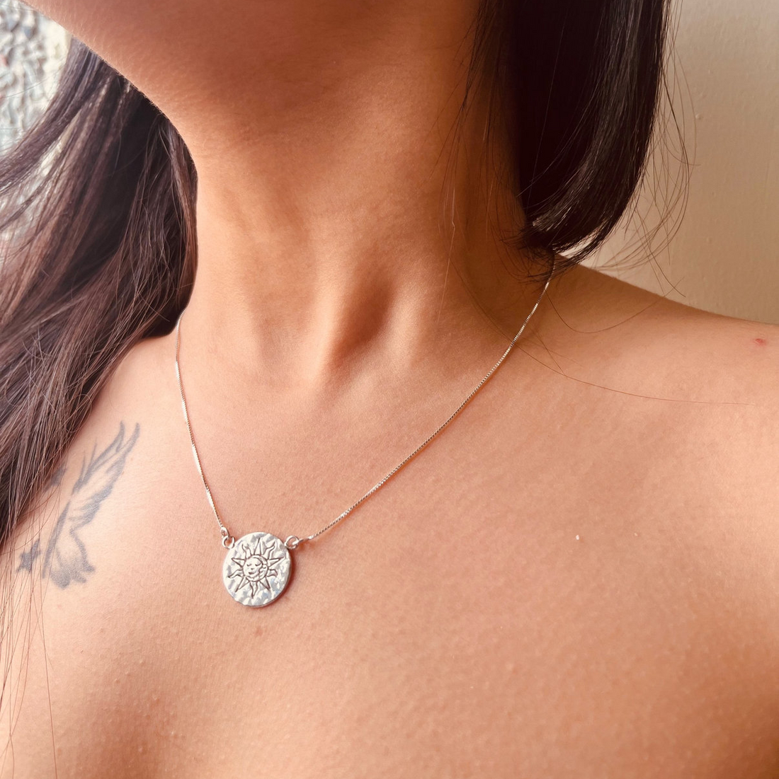 Close-up of a necklace with a pendant worn by a person.