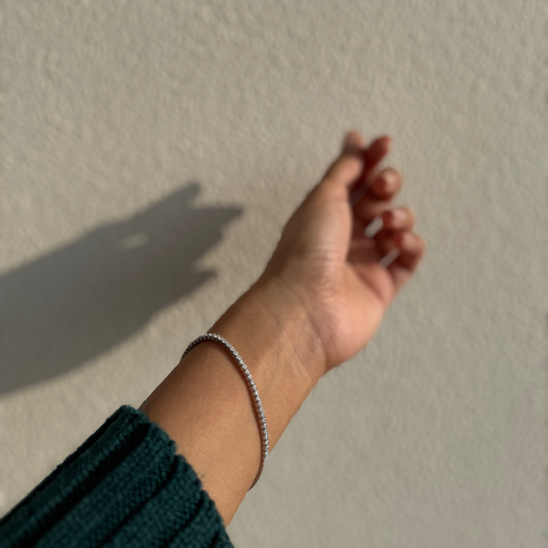 Hand with a bracelet against a plain wall