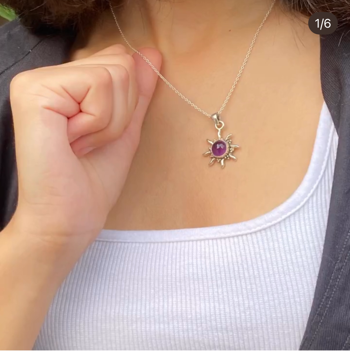 Necklace with a sun pendant worn by a person, displayed on a social media platform.