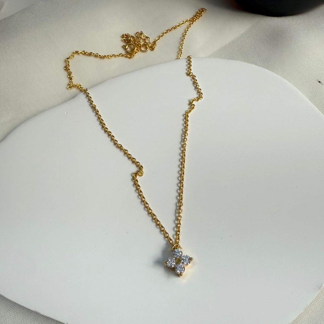 Gold necklace with floral pendants on a white stand