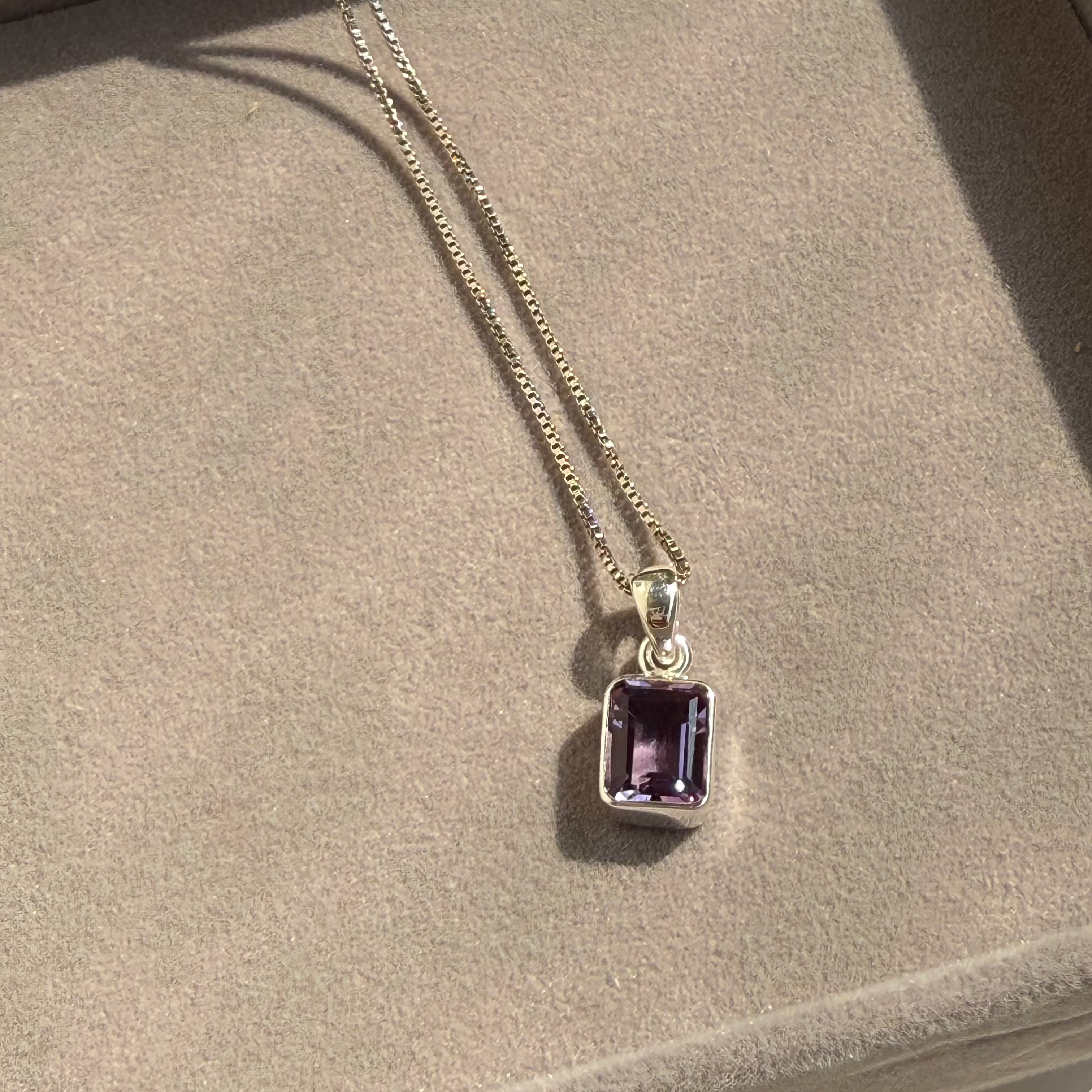 Necklace with a purple pendant on a textured surface