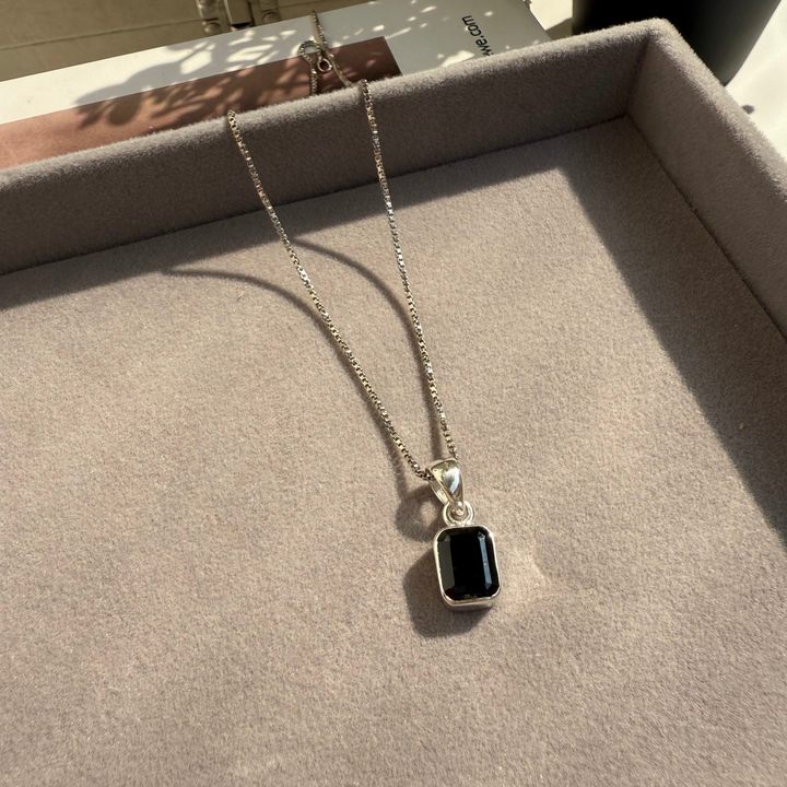 Necklace with a black pendant on a gray surface