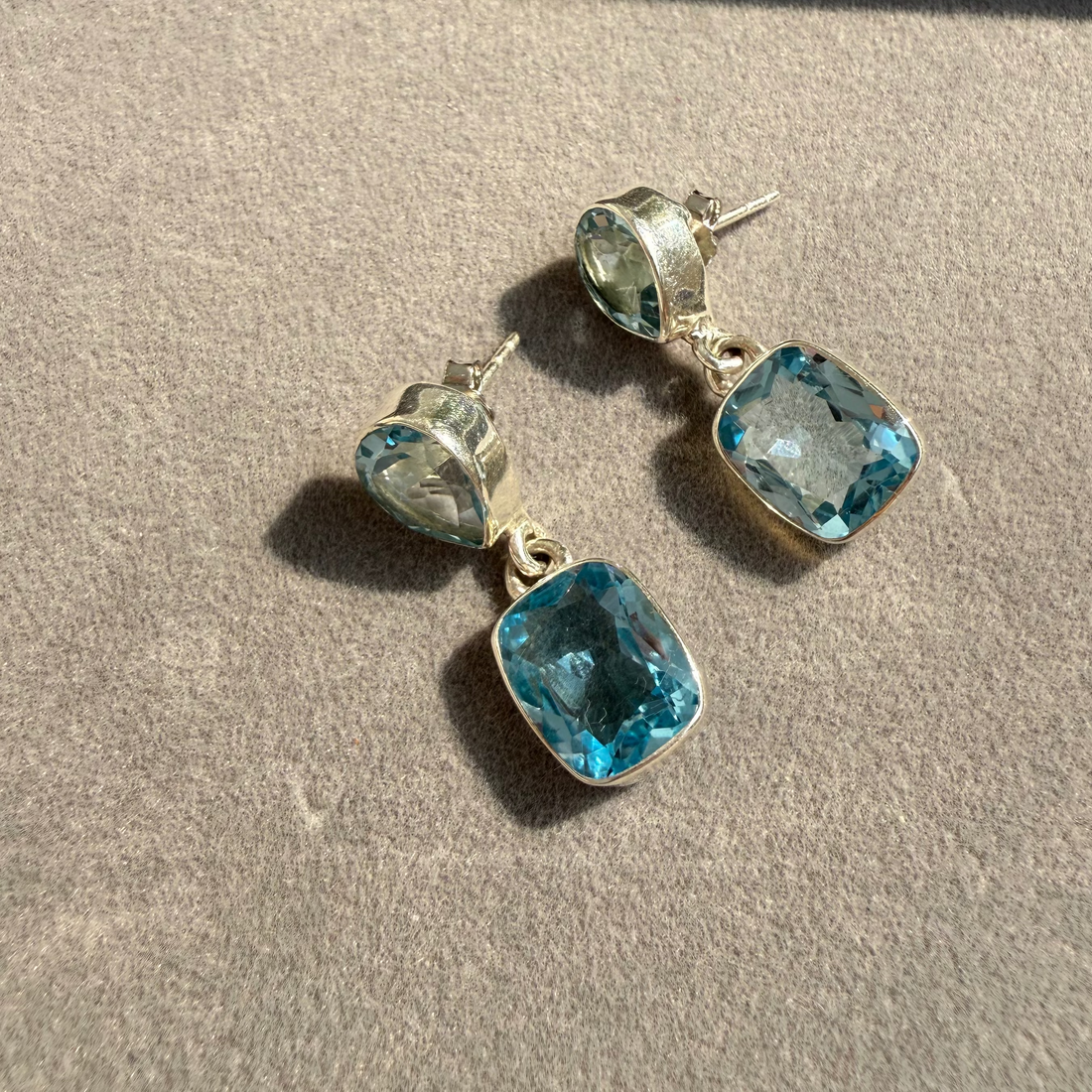 Pair of earrings with blue gemstones on a beige surface