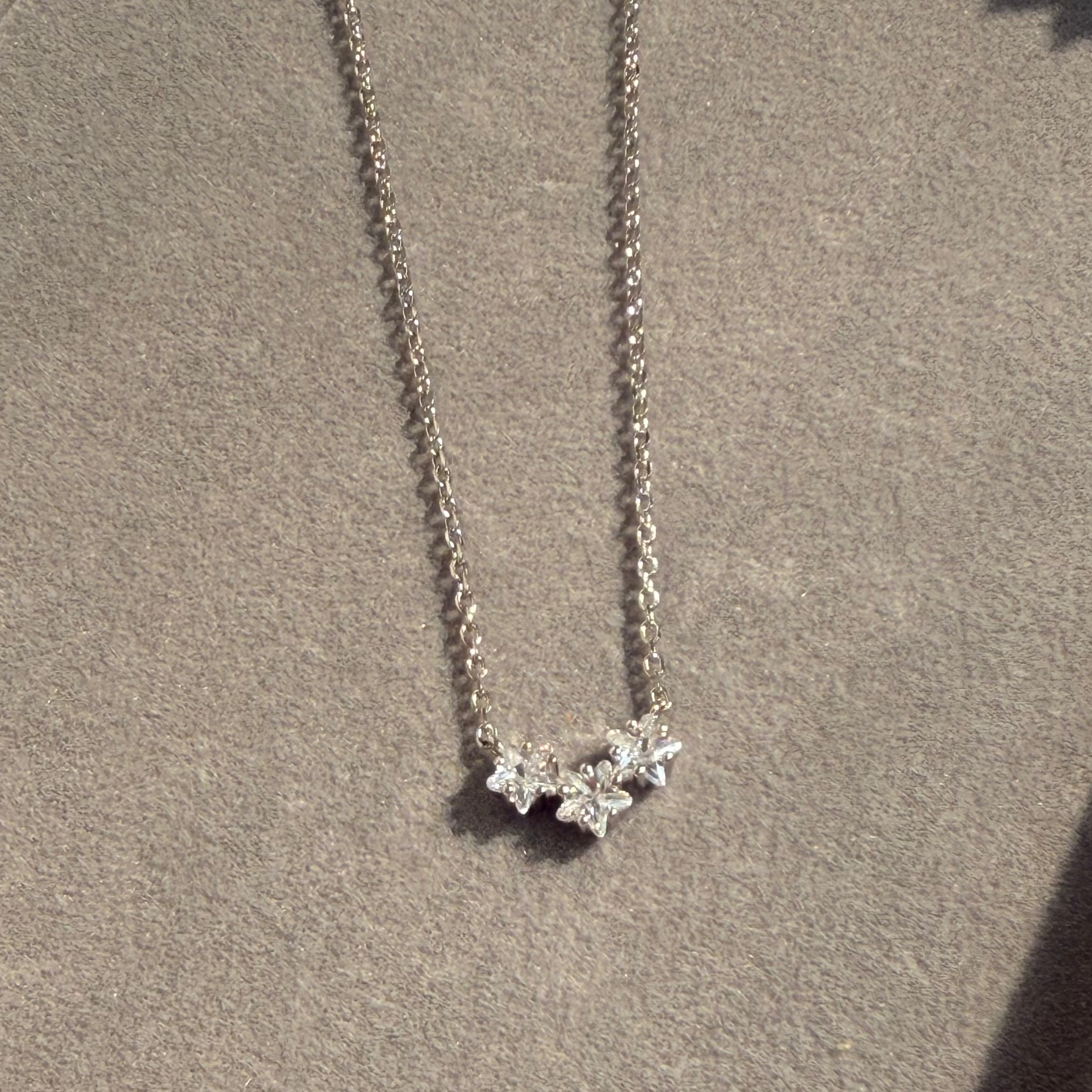 Silver necklace with a star-shaped pendant on a beige surface
