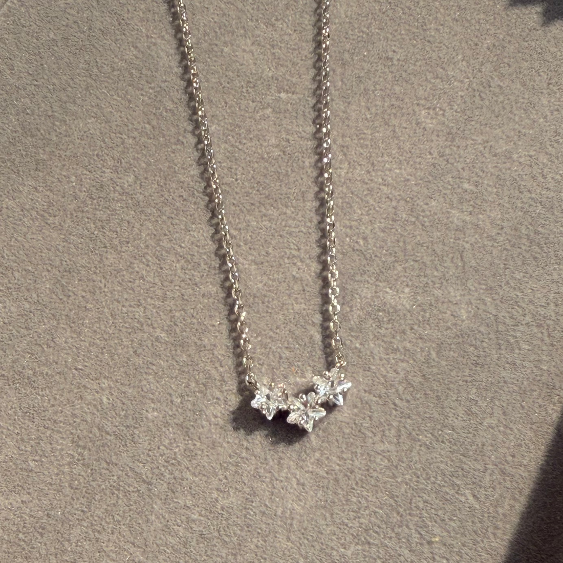Silver necklace with a star-shaped pendant on a beige surface