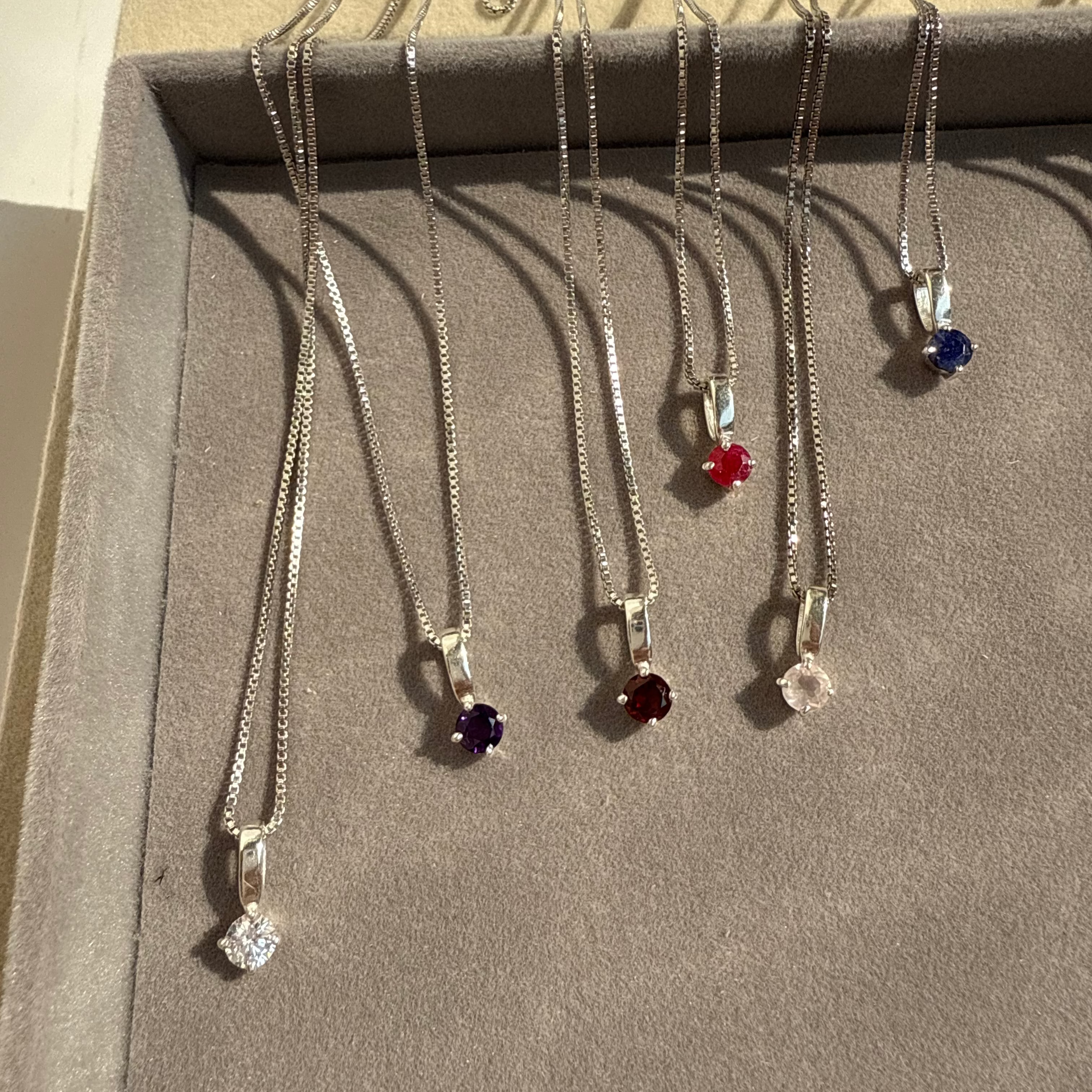 Set of necklaces with various pendants on a cardboard stand