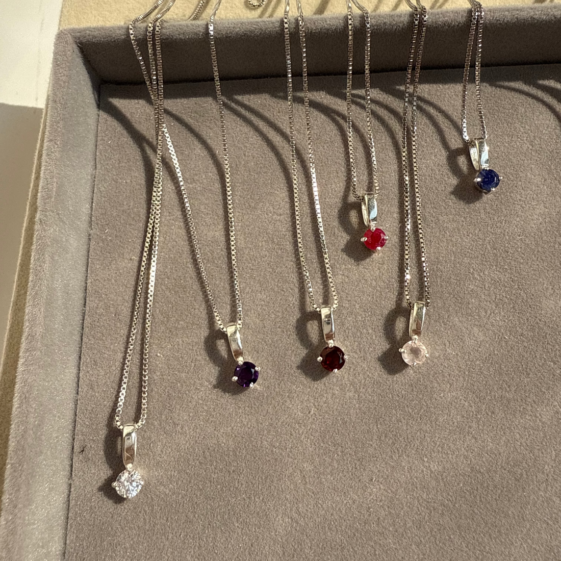 Set of necklaces with various pendants on a cardboard stand