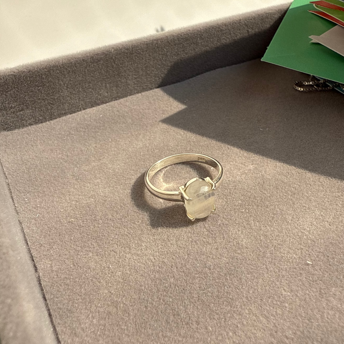 Silver ring with a clear gemstone on a textured surface