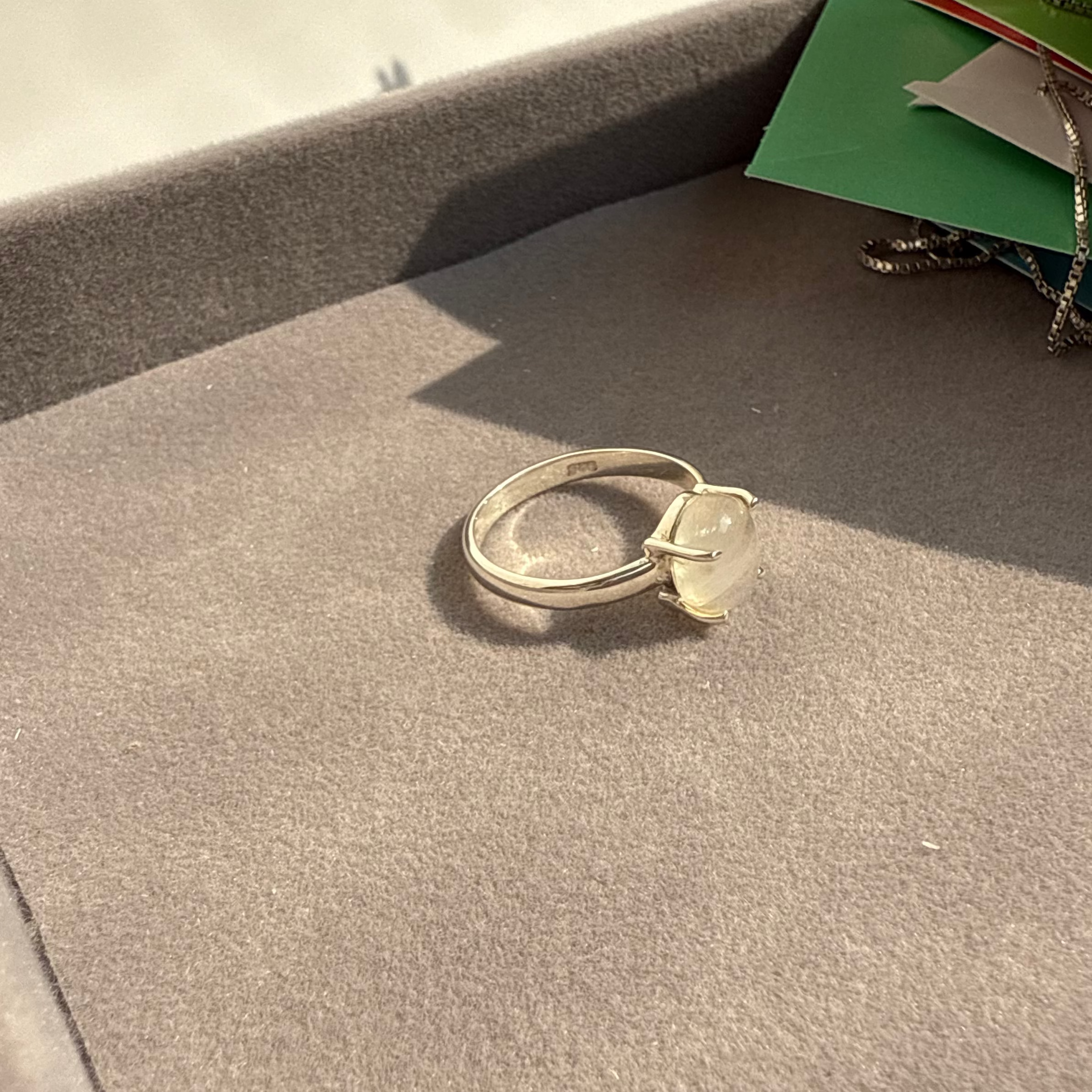 Silver ring on a gray surface with a colorful object in the background