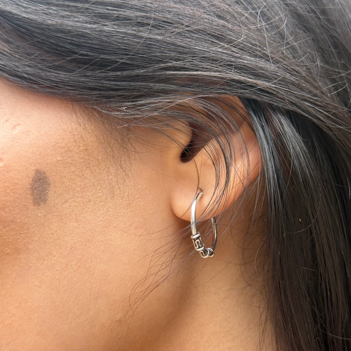 Close-up of an ear with a silver hoop earring and gray hair.