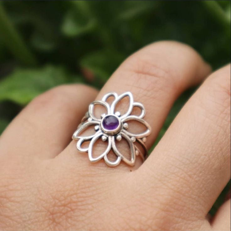 Silver ring with a purple gemstone on a hand, displayed on a social media platform.